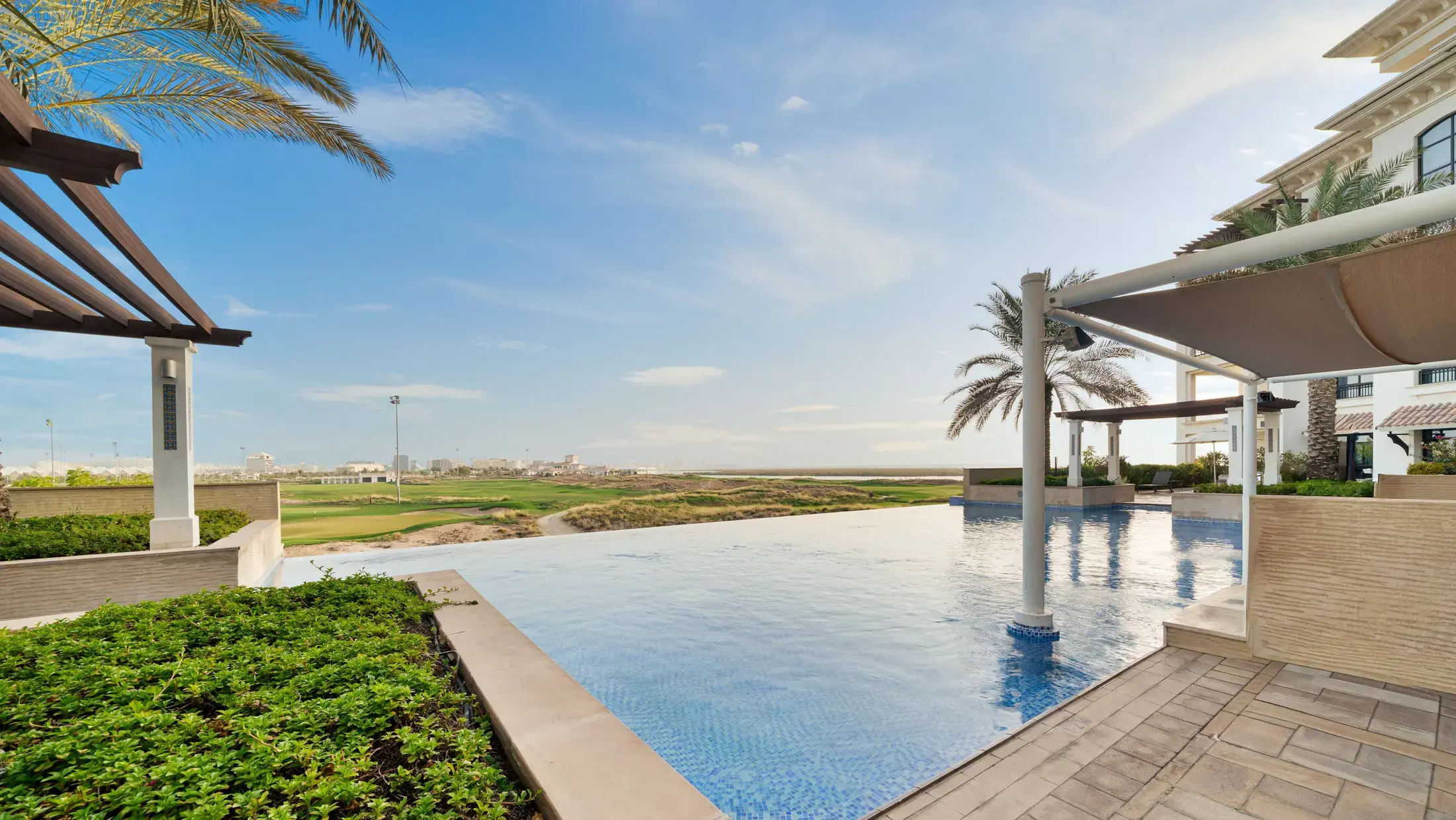 A golf course seen across an infinity pool from a residential terrace