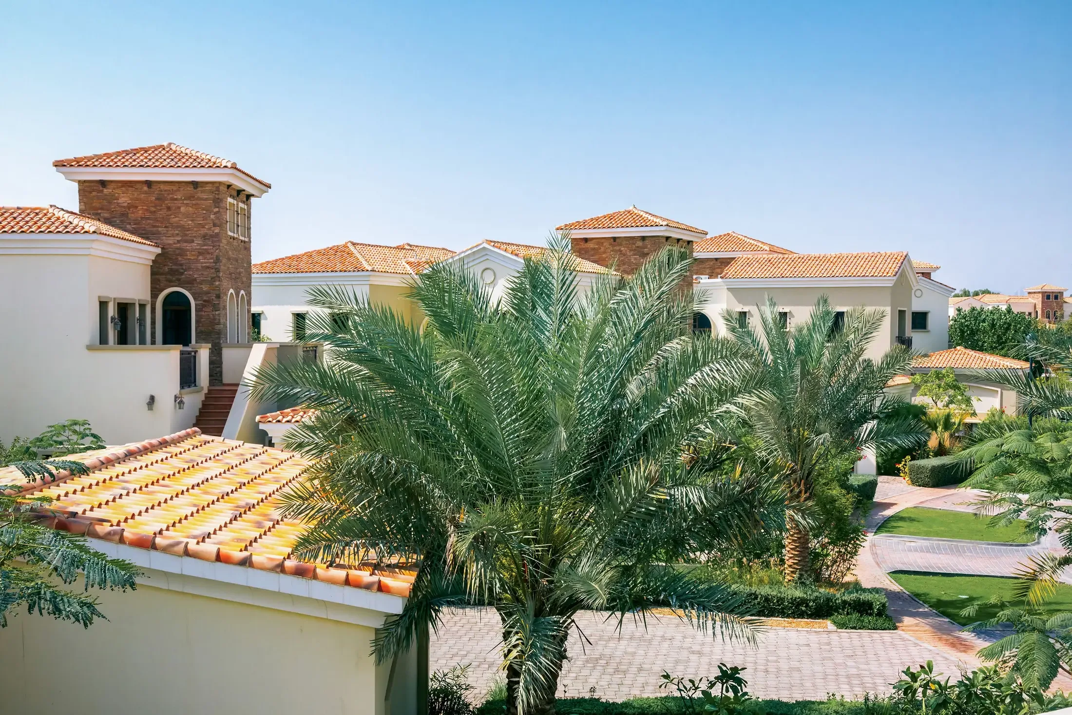 Tile-roofed villas among mature palms in a landscaped community