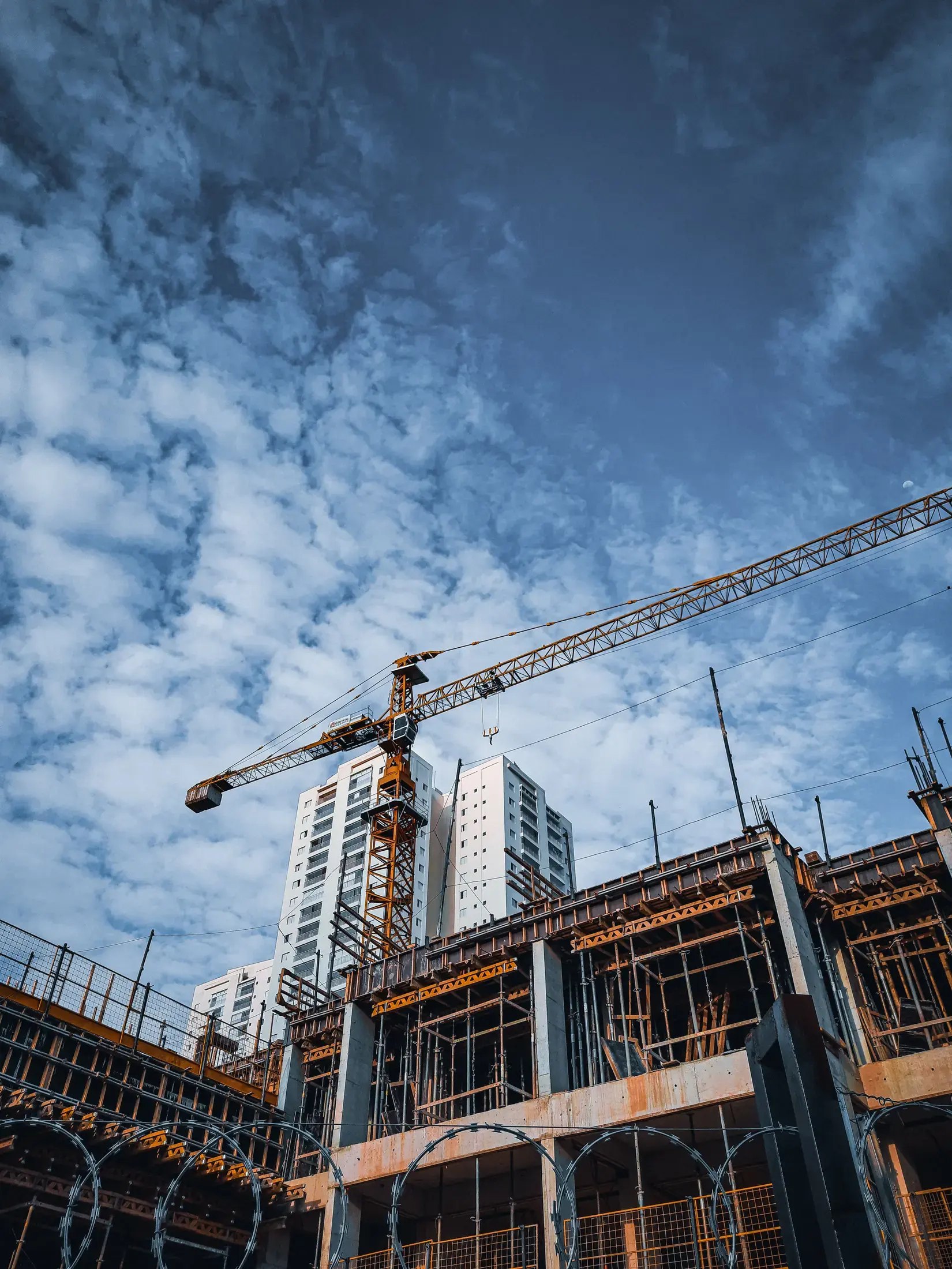 A reinforced concrete frame and tower crane on a residential construction site