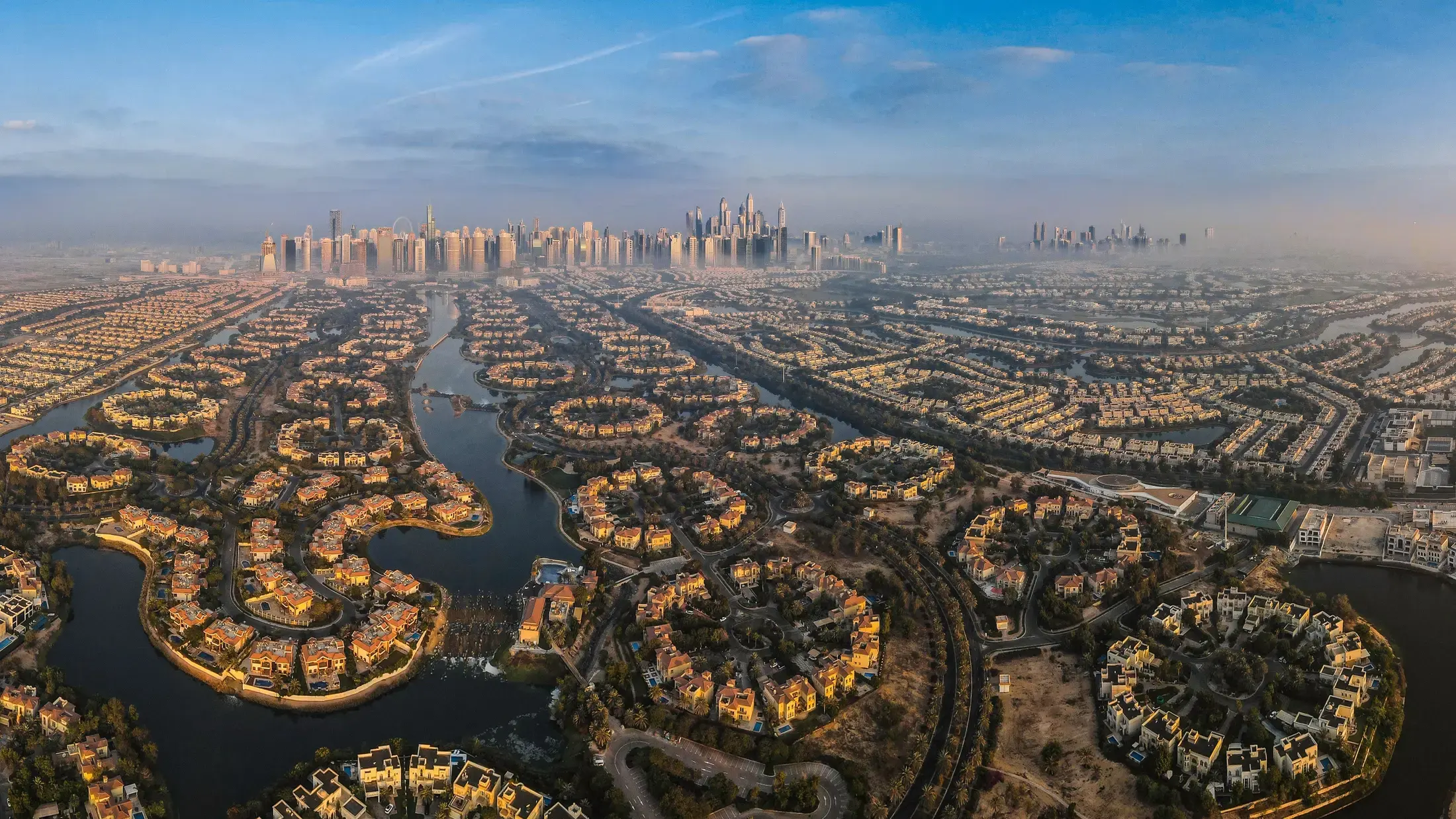 Villa communities laid out around lakes, with a distant city skyline