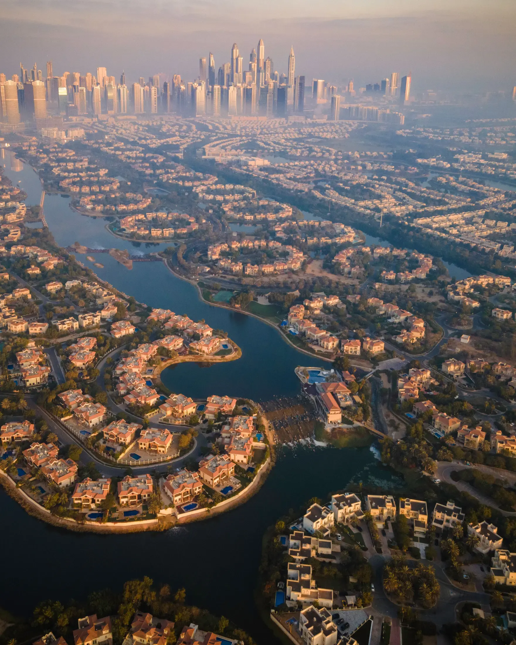 A villa community at golden hour, lakes threading between the houses